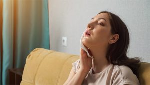 Brunette woman suffering from the heat, wiping herself off with a paper napkin because no air conditioning